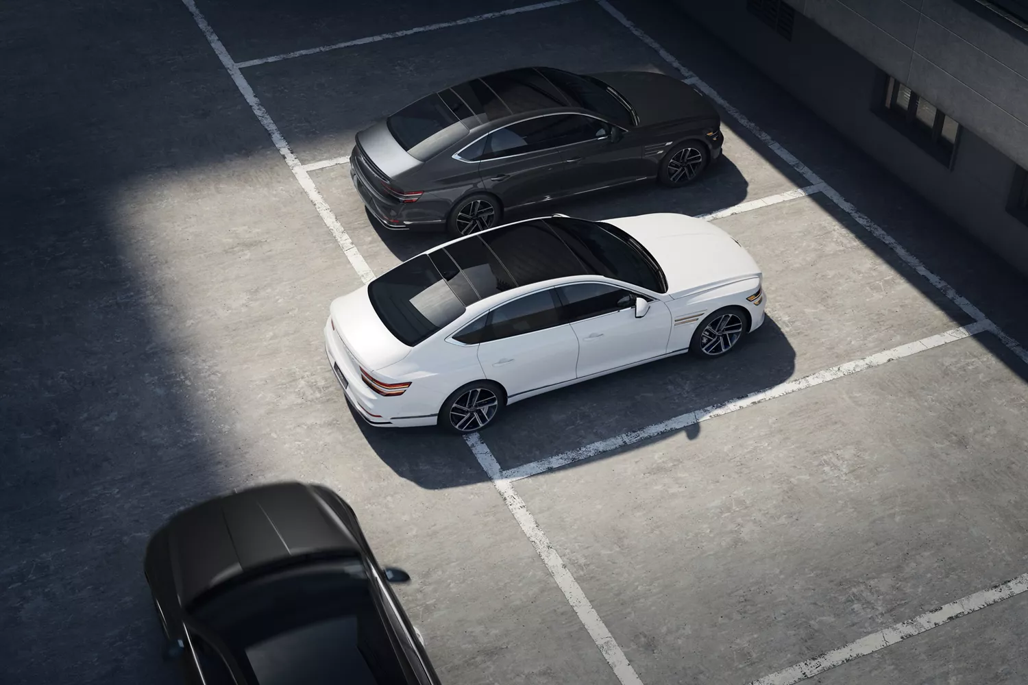 Aerial view of white Genesis G80 parking in garage with black vehicles parallel and perpendicular