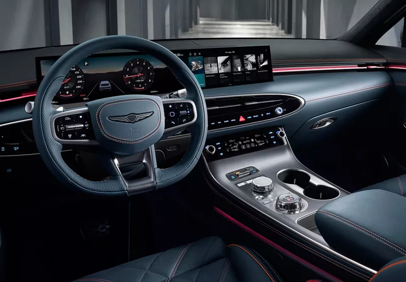 Luxury car interior featuring a digital instrument cluster, wide infotainment display, leather-wrapped steering wheel with control buttons, and a sleek center console with rotary dials and ambient lighting