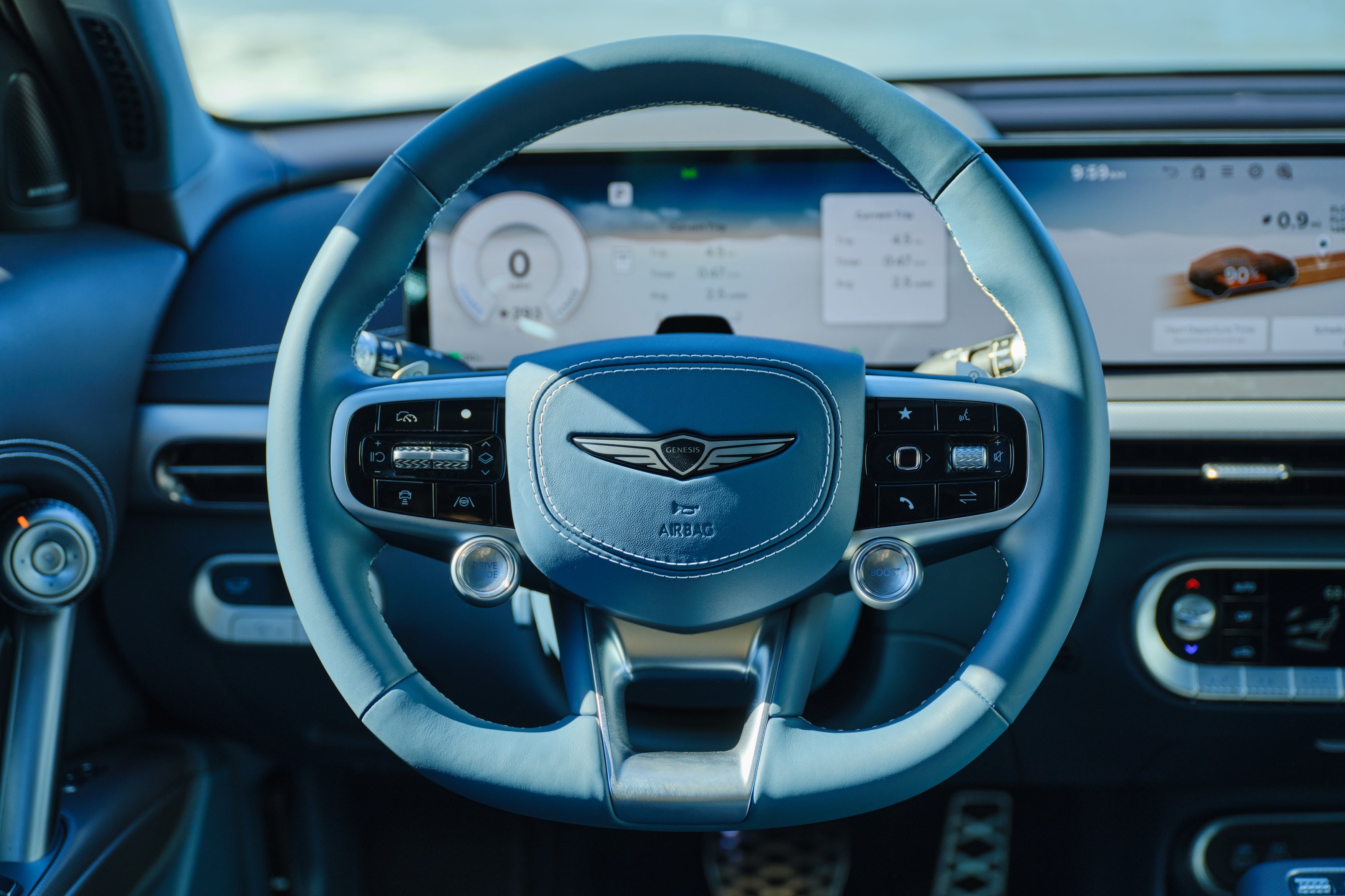 This is a POV of the driver looking at the steering wheel of the 2026 Genesis GV60, highlighting the 27 inch display screen for the dash and console.