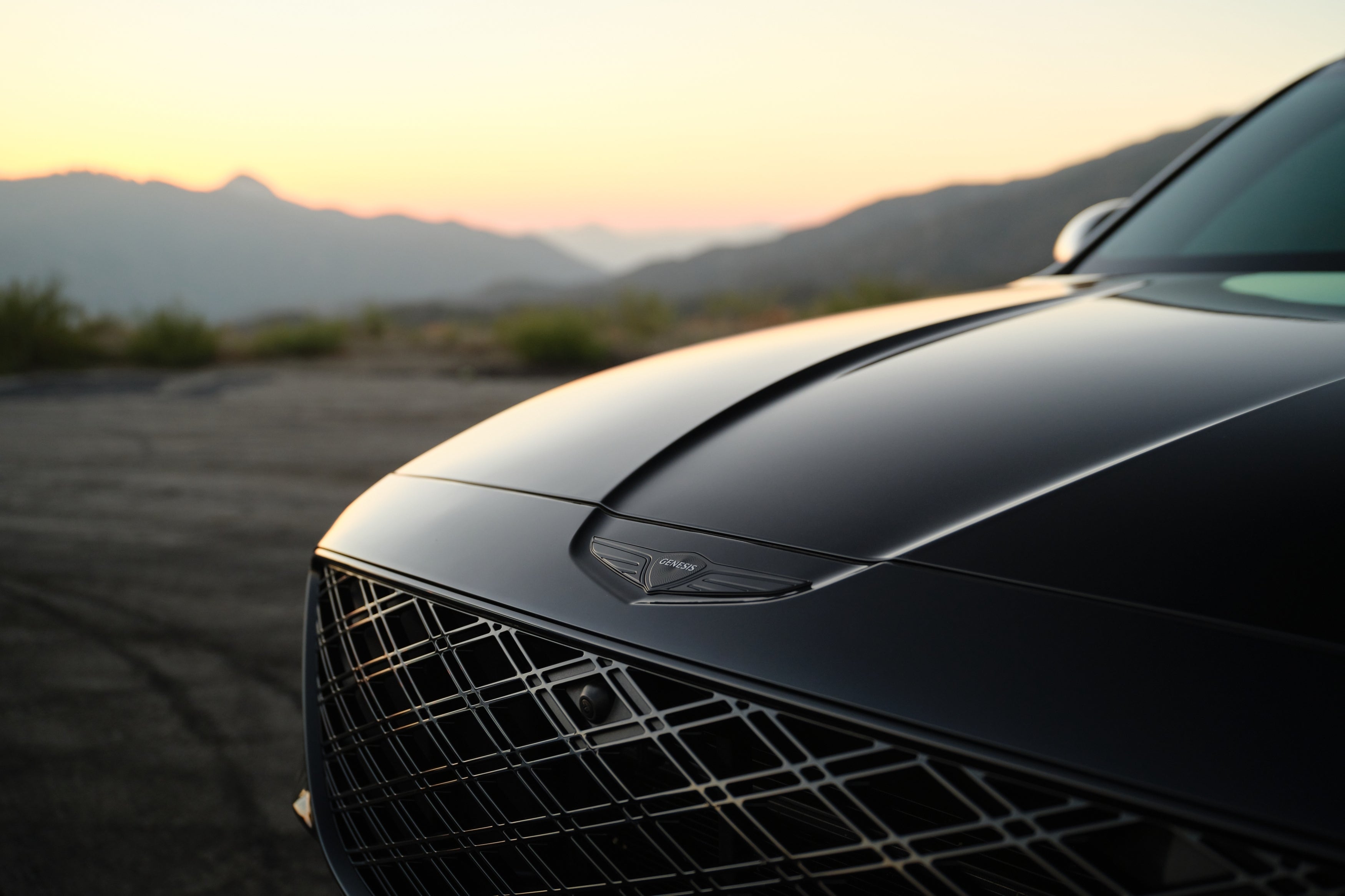 A closeup shot of the front of the new Genesis GV80 pointed to the left with arid ridges in the background.